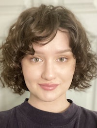 a woman with curly hair is posing for a photo